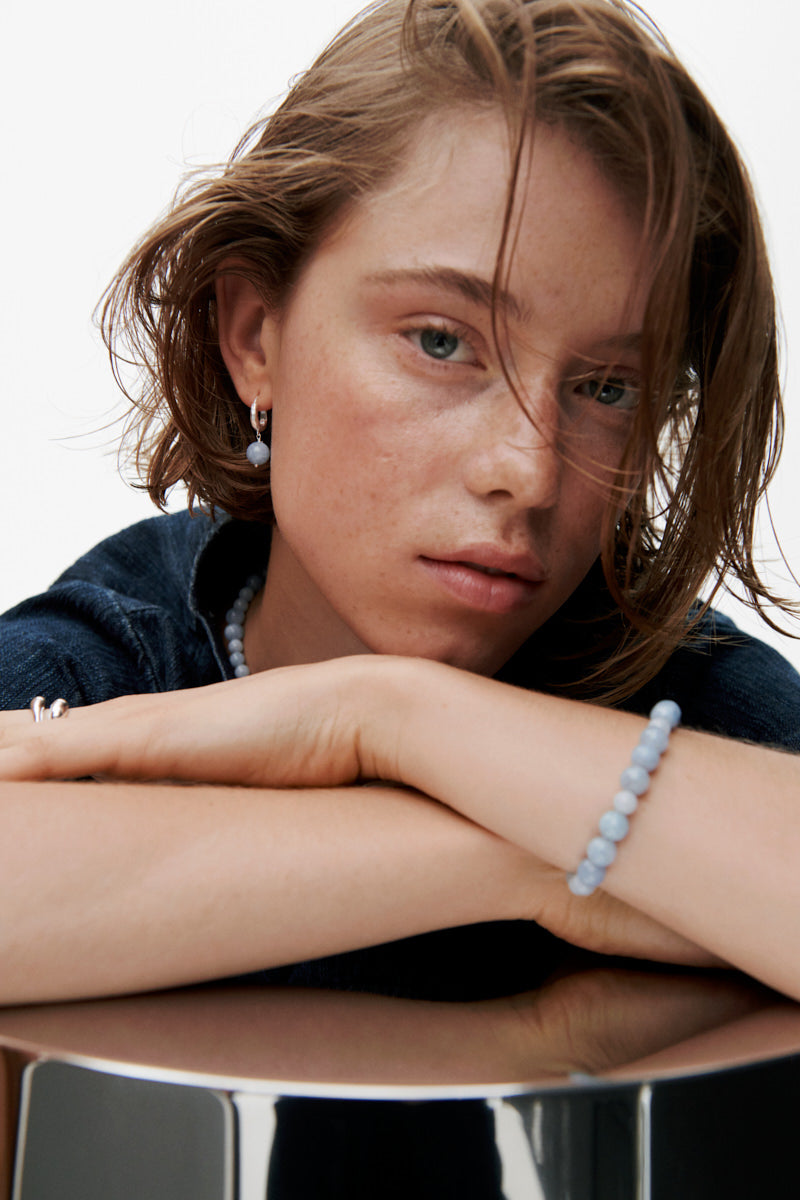 Model trägt filigranes Blue Sky Armband aus vergoldetem Silber mit blauen Achatsteinen am Handgelenk