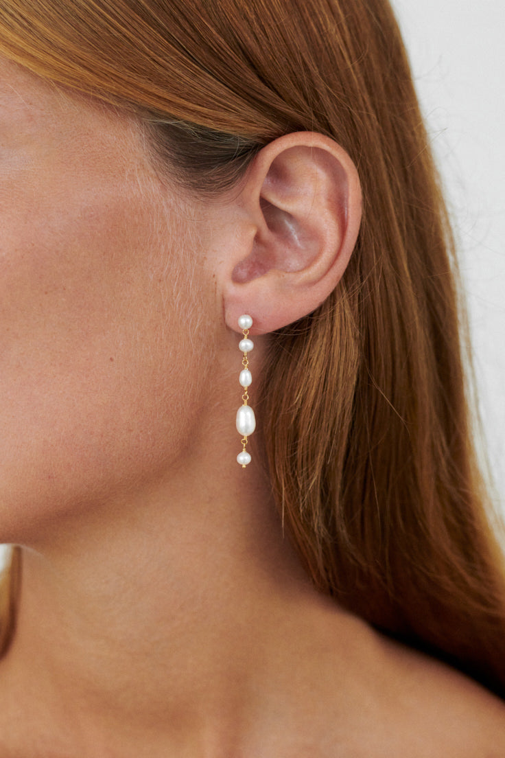 Pernille Corydon Ohrringe White Dreams in Gold am Ohr eines Models