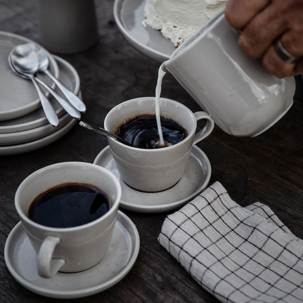 Sandfarbene Kaffeetasse mit Untersetzer von ERNST in der Kaffeepause