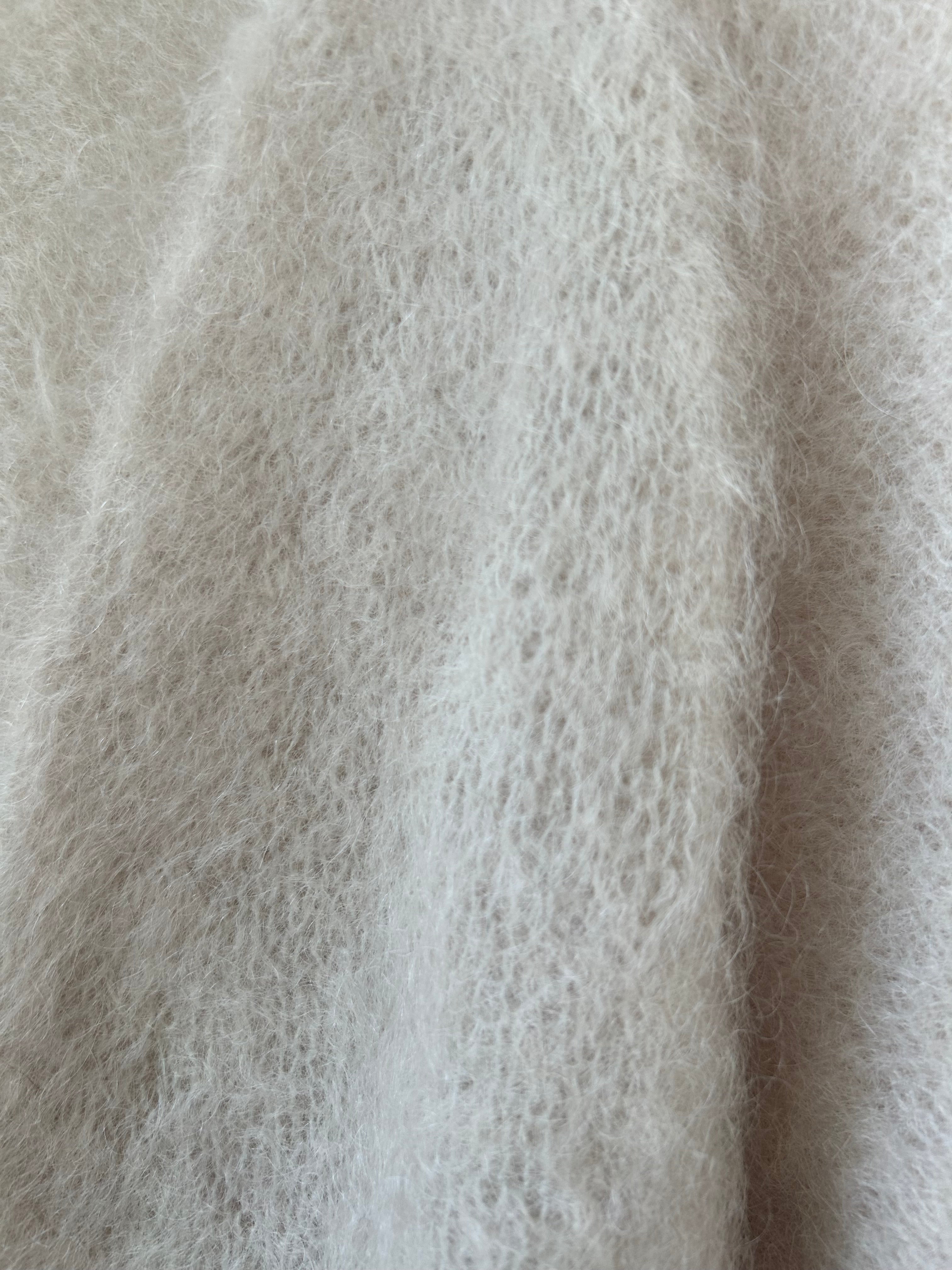 Nahaufnahme der Strickjacke aus Mohair in Creme, Perlmuttknöpfe und weiche Strickstruktur