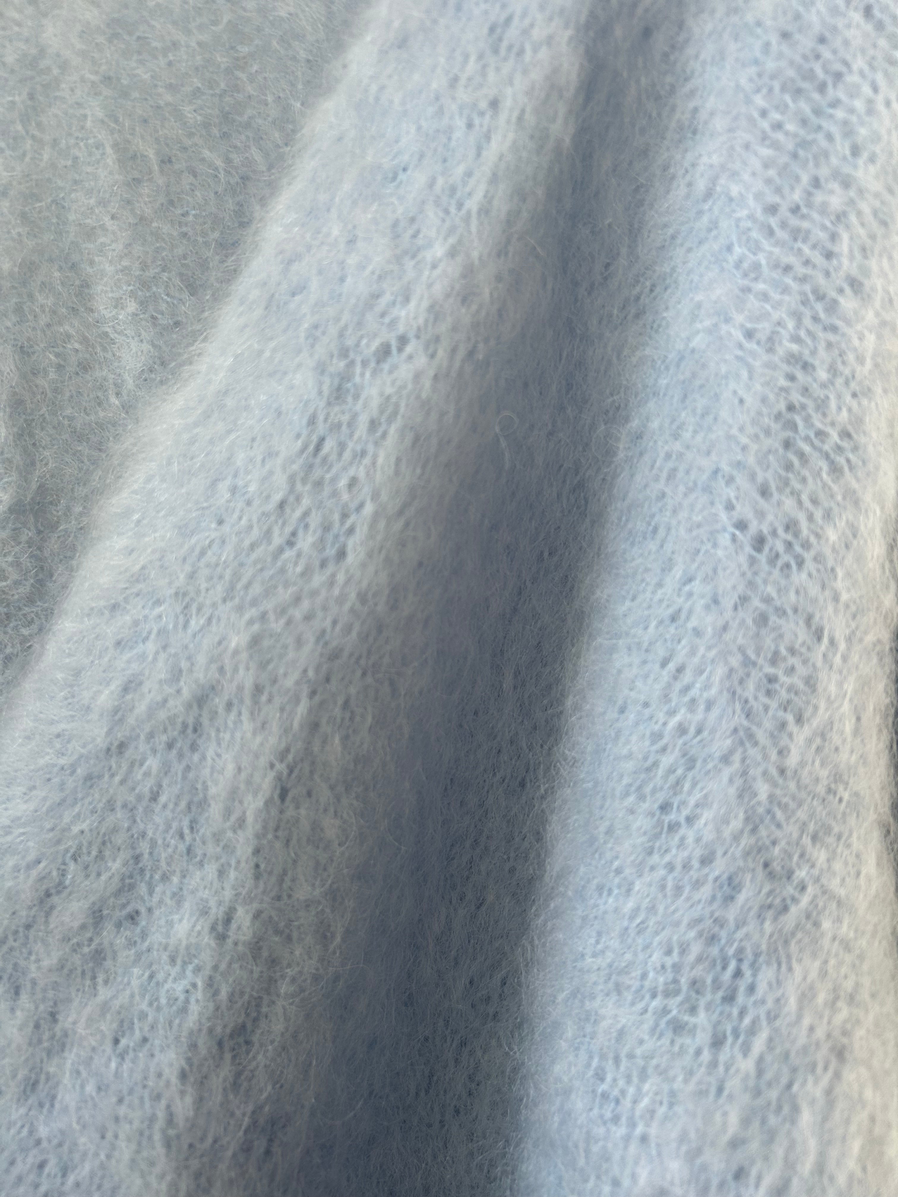 Nahaufnahme der Strickjacke aus Mohair in Eisblau, Perlmuttknöpfe und weiche Strickstruktur